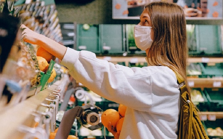 A lady shopping groceries in food store wearing a face mask