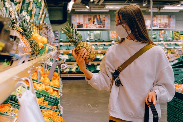 woman wearing mast shopping goof and groceries in a supermarket.