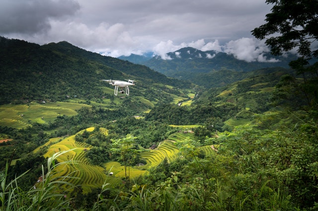 a white drone inspecting a crop farm in a remote farm