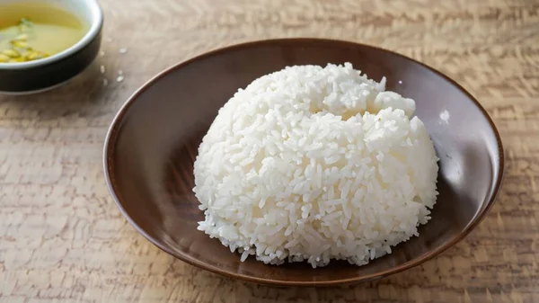 Steamed jasmine rice ceramic bowl over wooden background. top view