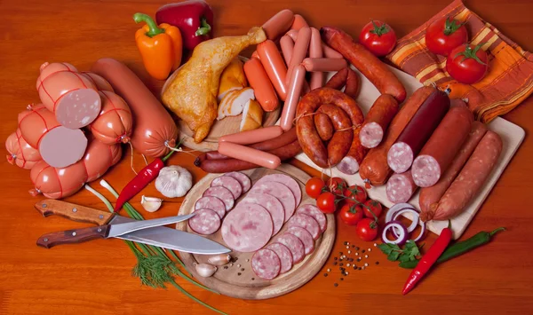 A variety of processed cold meat products, on a wooden cutting board.