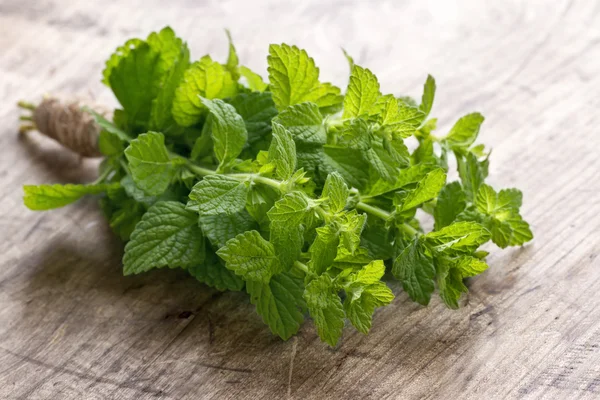 Bunch of green fresh mint herbs on rustic wooden table background