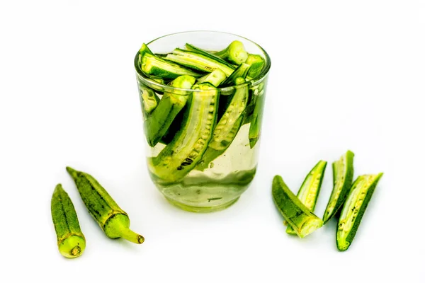 Popular Okra drink isolated on white with some okra pods in water and some of them on the surface and isolated on white.